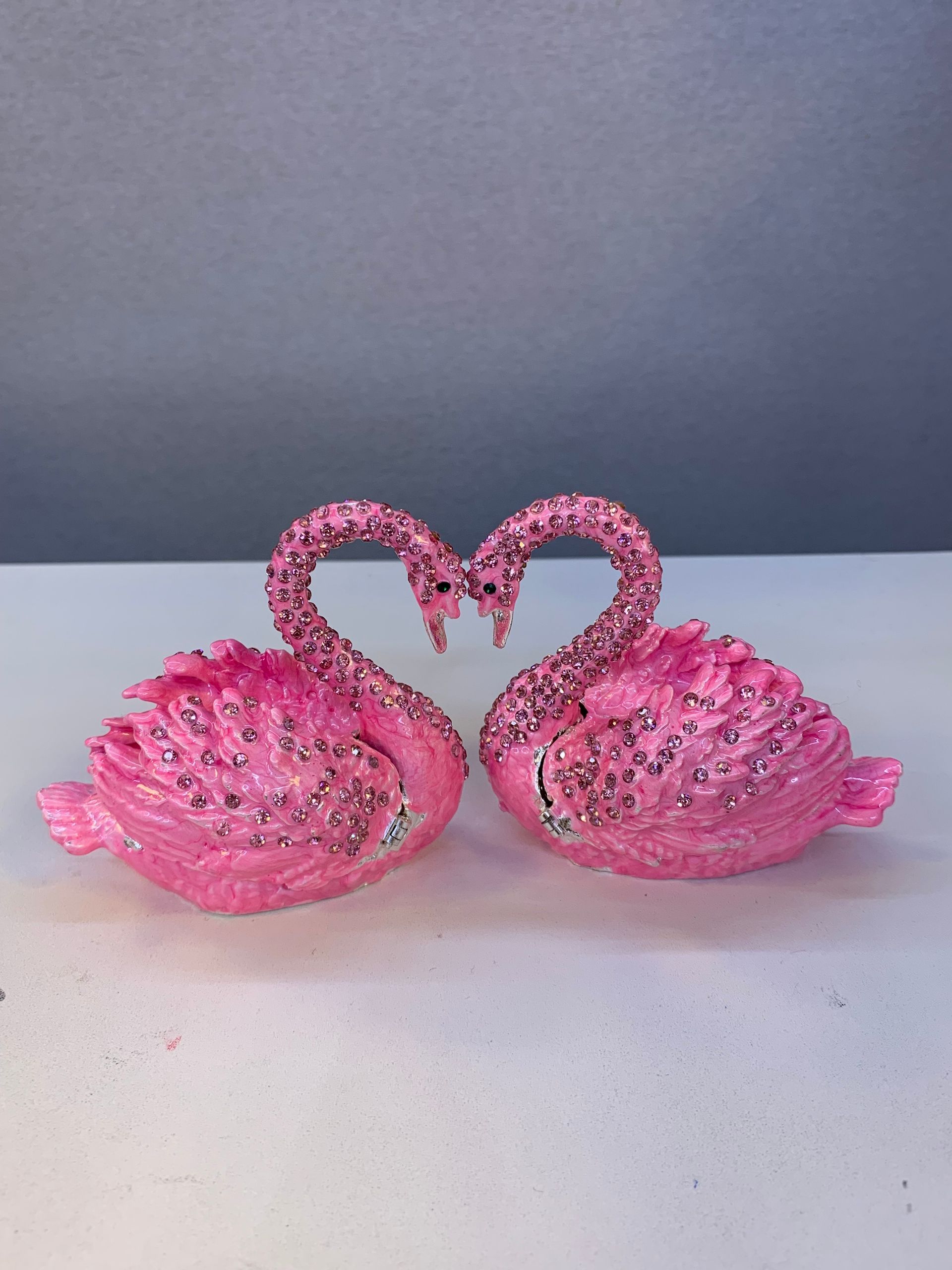 Two pink swans are sitting next to each other on a table.