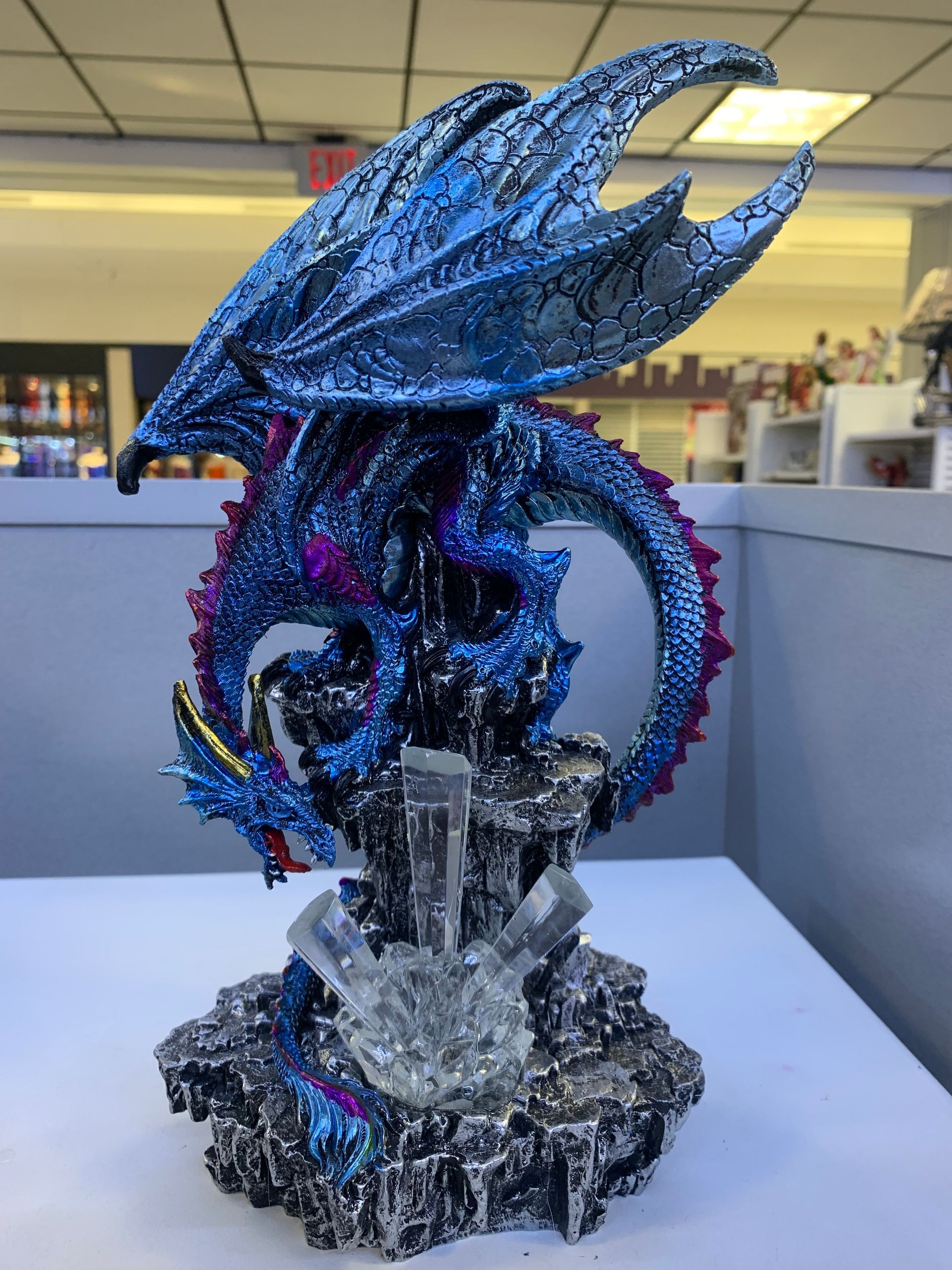 A statue of a blue dragon sitting on a rock