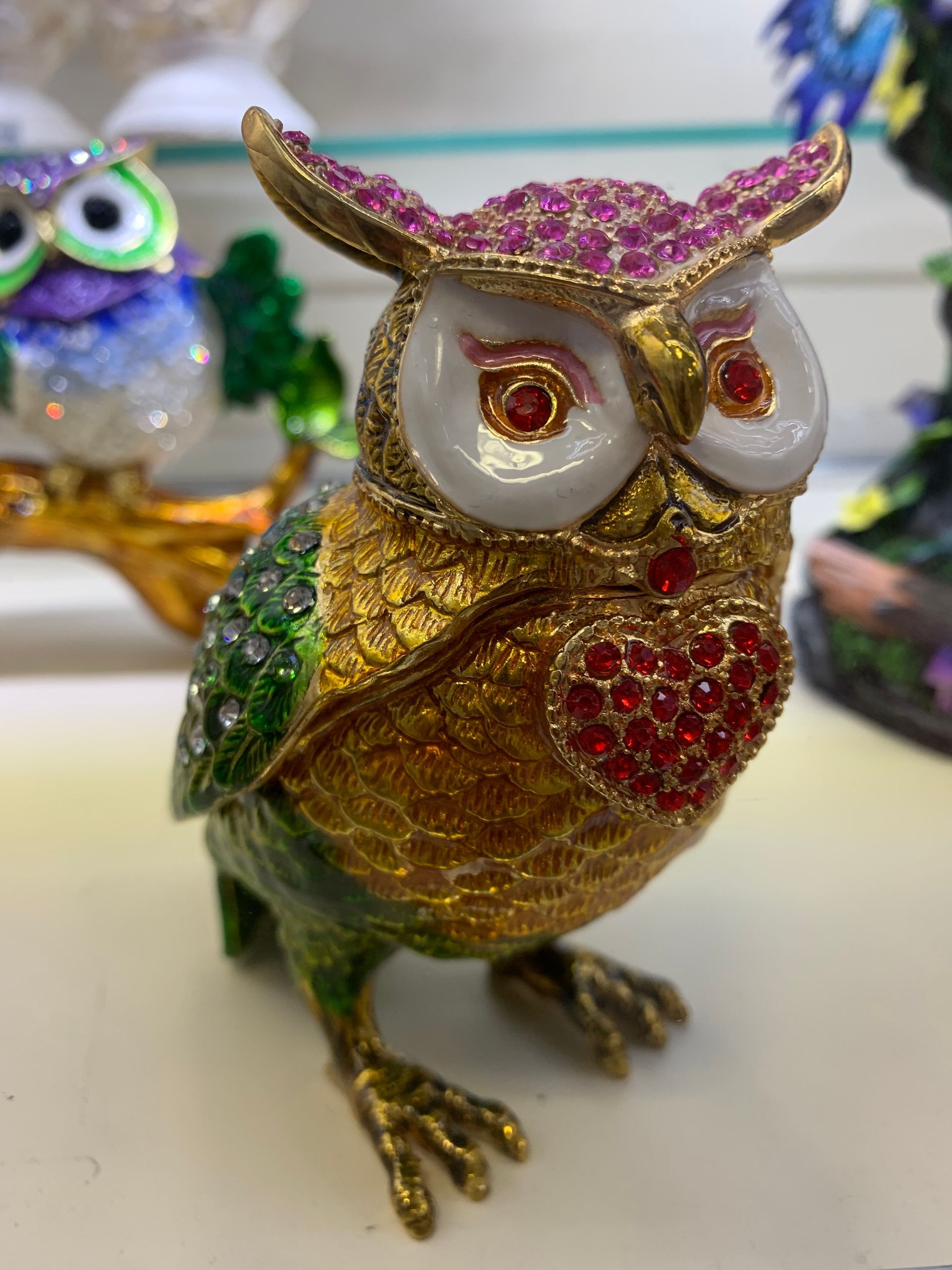 A gold and green owl with a heart on its chest