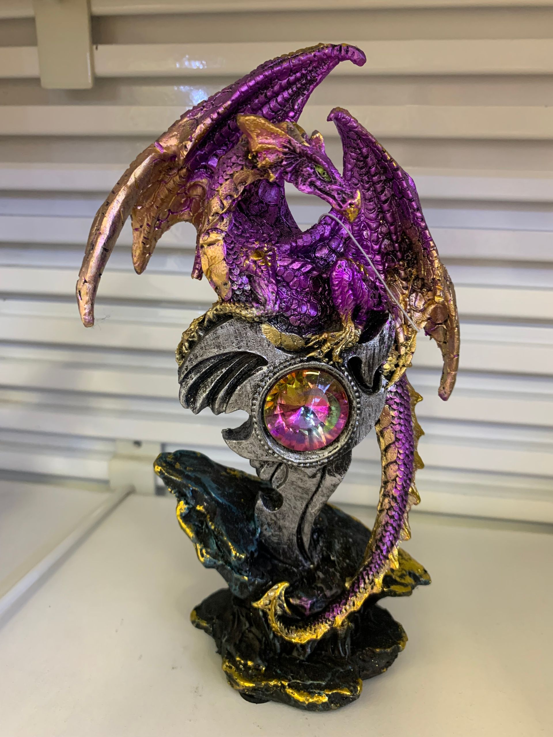 A purple and gold dragon statue is sitting on a table.
