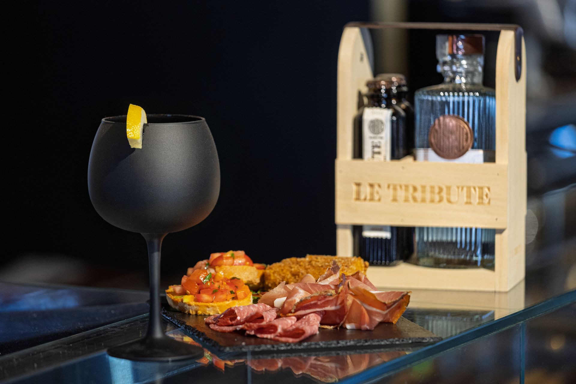 Cocktail nero, salumi e una cassa di legno per bottiglie con l'etichetta 