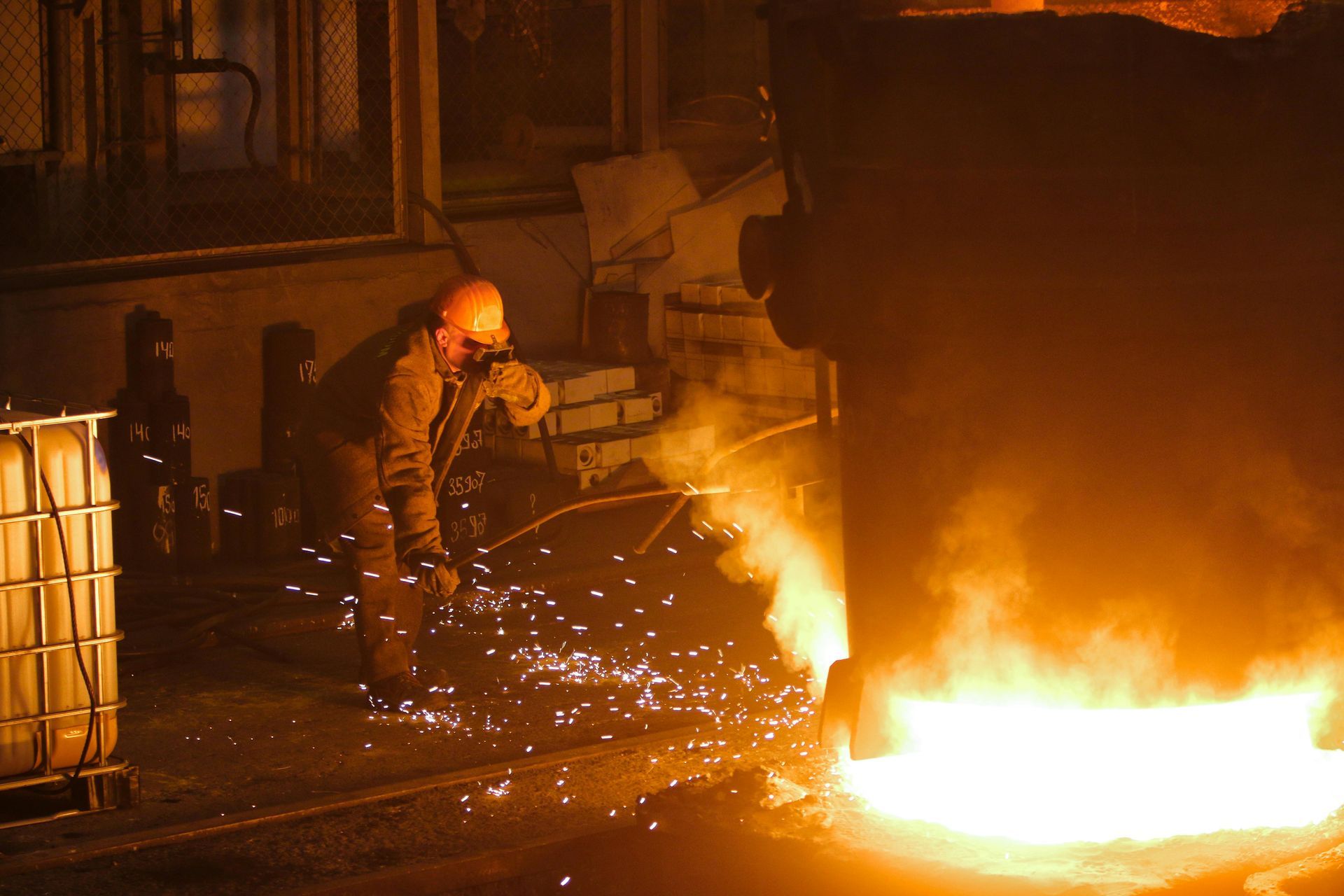 A man is cutting metal with a torch in a factory.