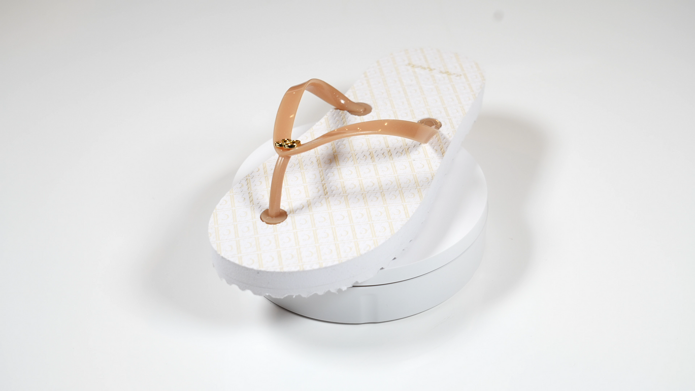 A pair of white flip flops with brown straps on a white surface.