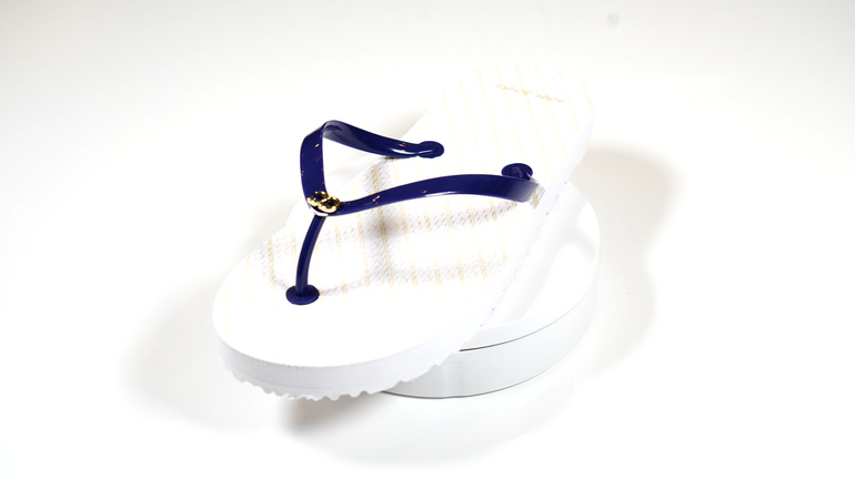 A pair of white flip flops with a blue strap