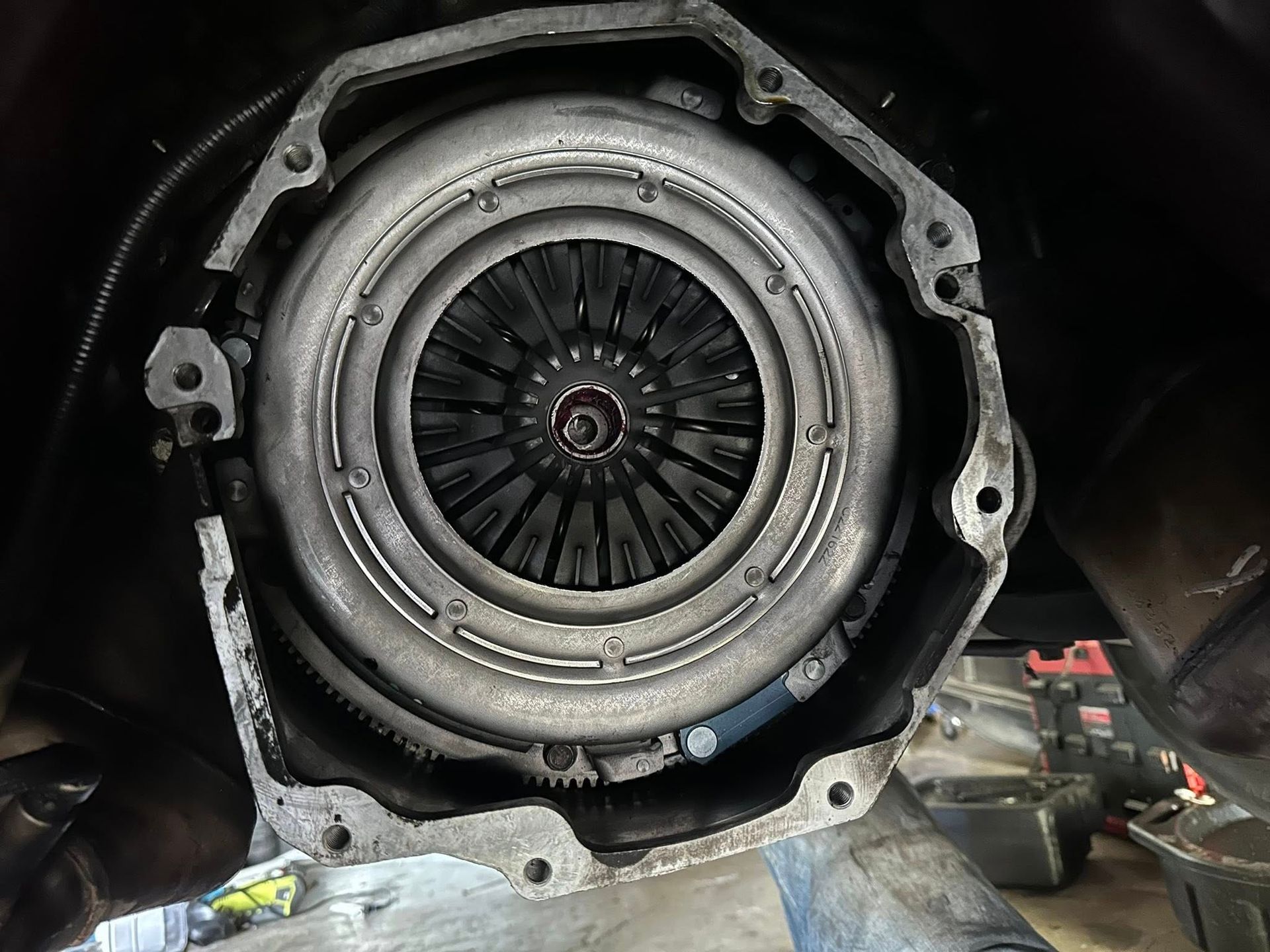 A car clutch assembly attached to the engine flywheel, viewed from inside the bell housing during a repair.