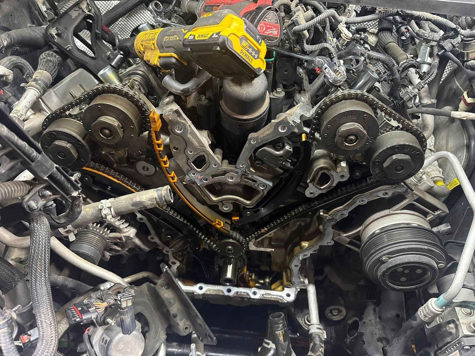 Engine front cover removed showing the timing chain assembly and gears on a disassembled automotive V6 engine.