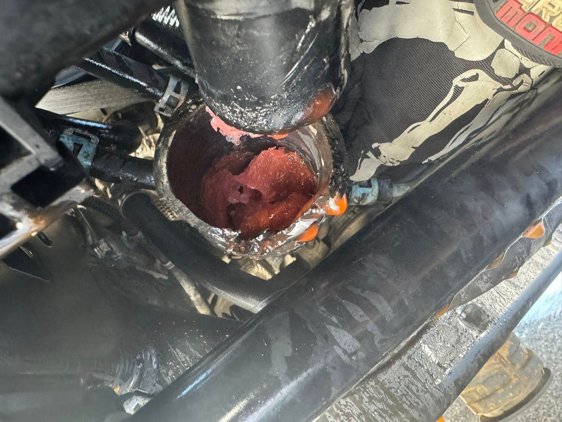 A close-up view of an open fuel filter housing filled with a thick, reddish-brown, gel-like substance.