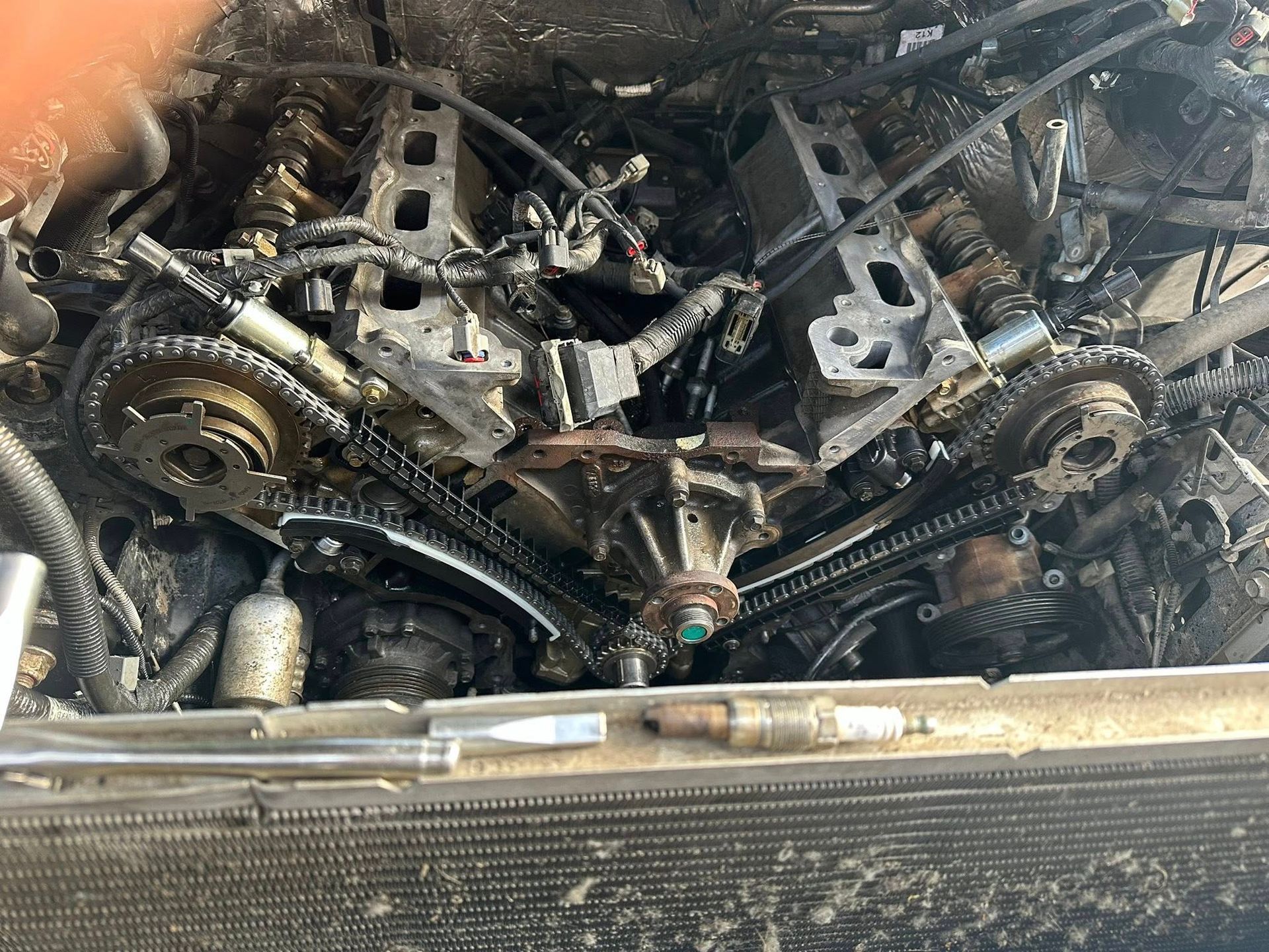 A disassembled V6 engine block with visible timing chains, gears, and metallic components in an engine bay.