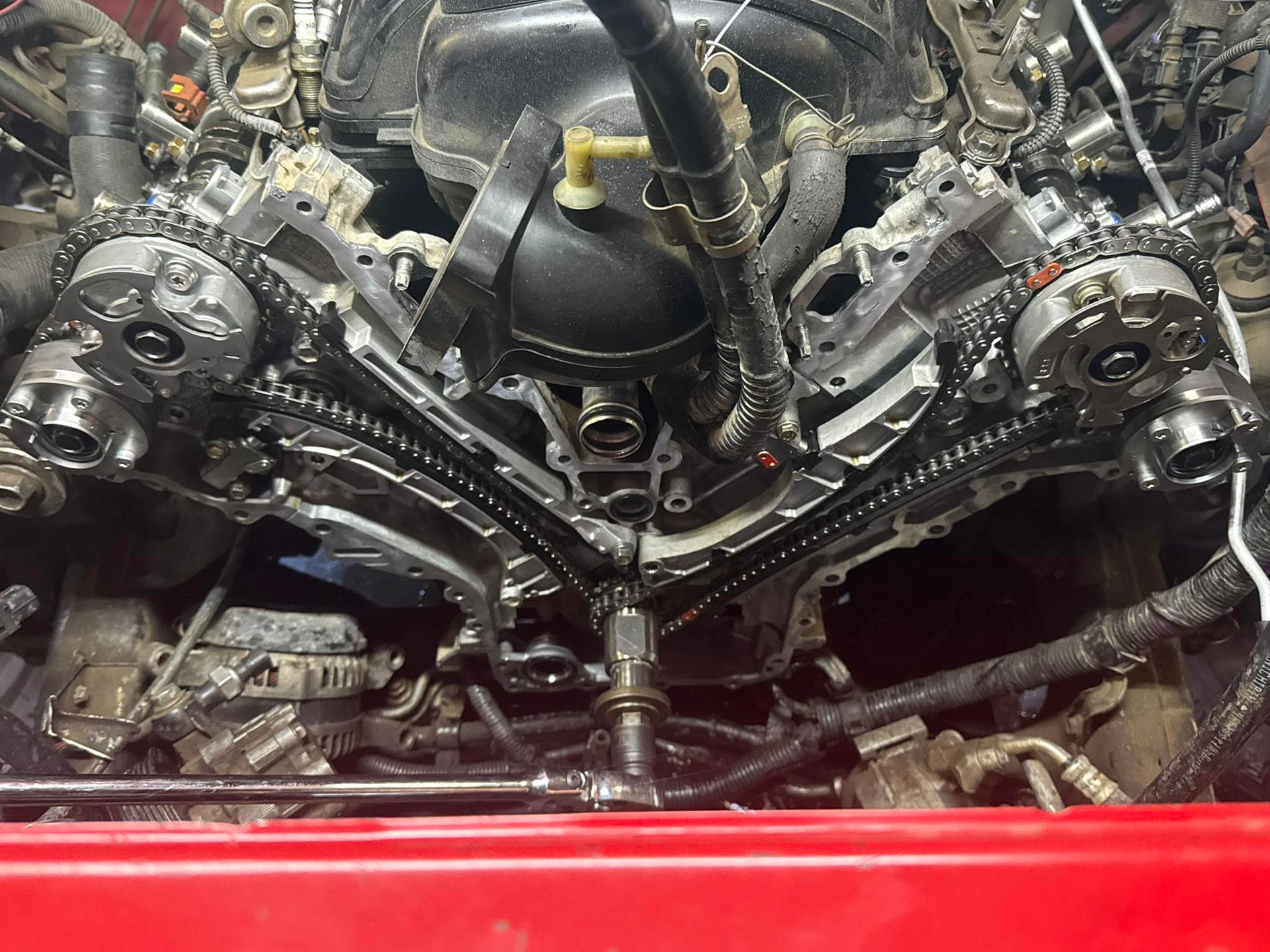 The front view of a car engine with exposed timing chains and gears, partially disassembled for maintenance or repair.