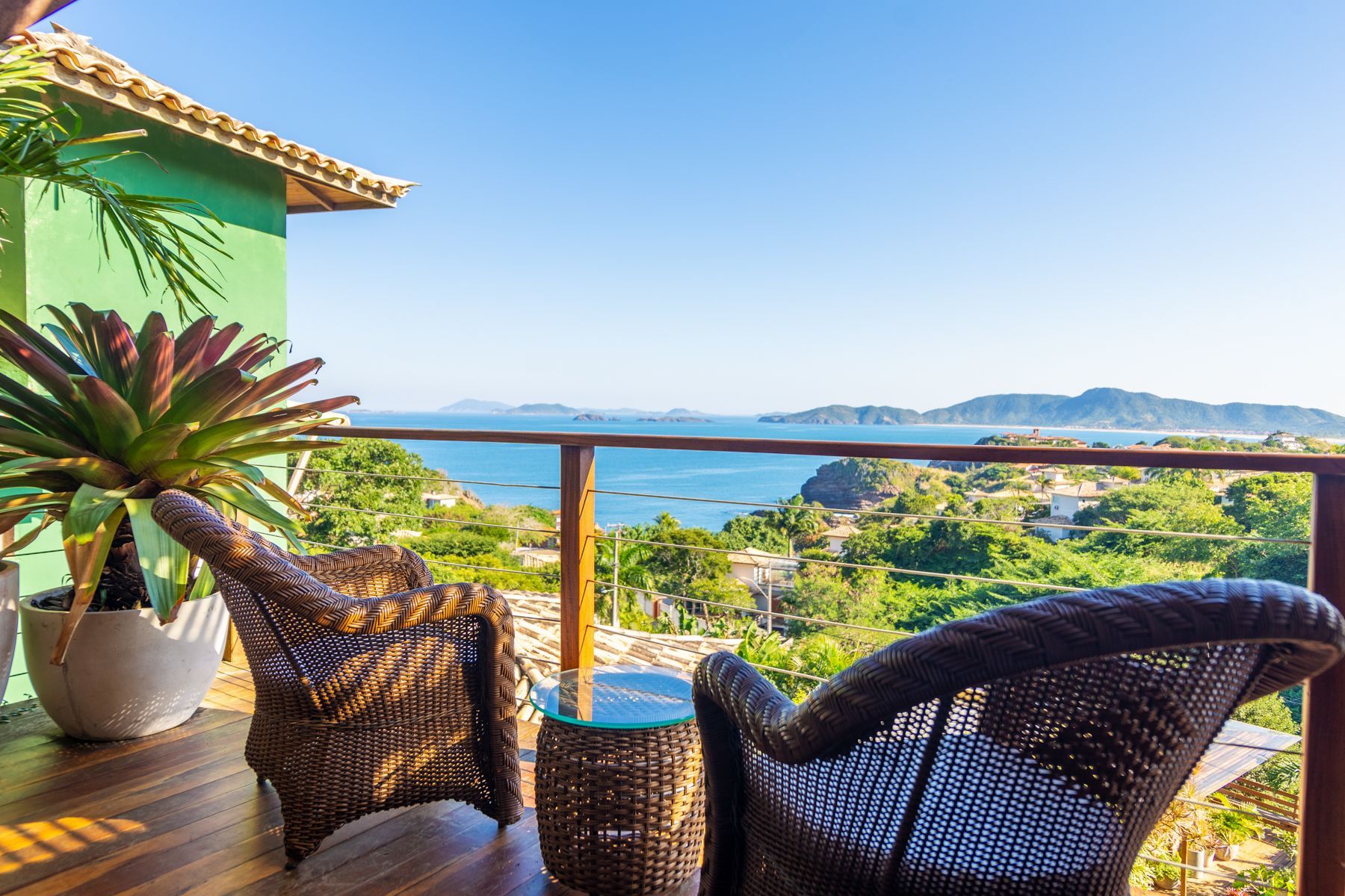 Duas cadeiras de vime estão sentadas em uma varanda com vista para o oceano.