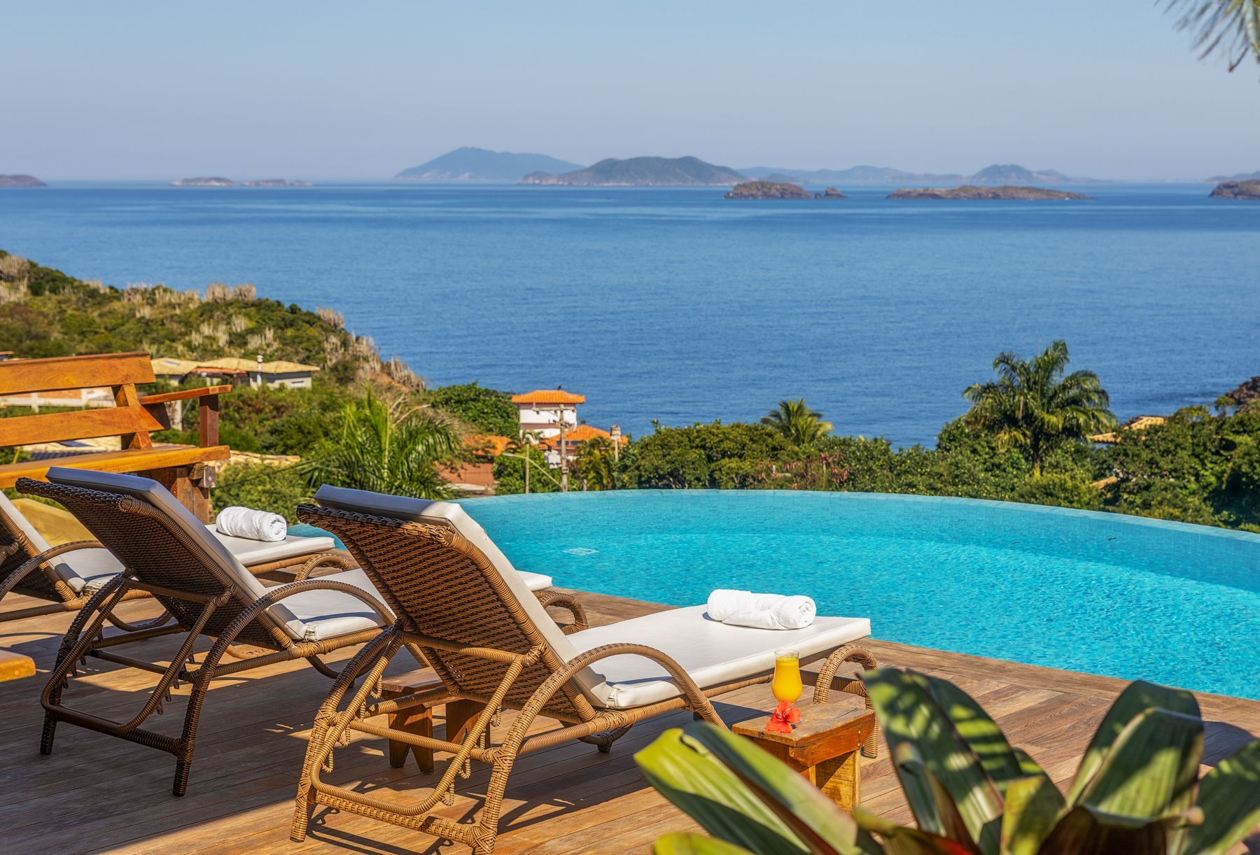 Uma piscina com cadeiras ao redor com vista para o oceano