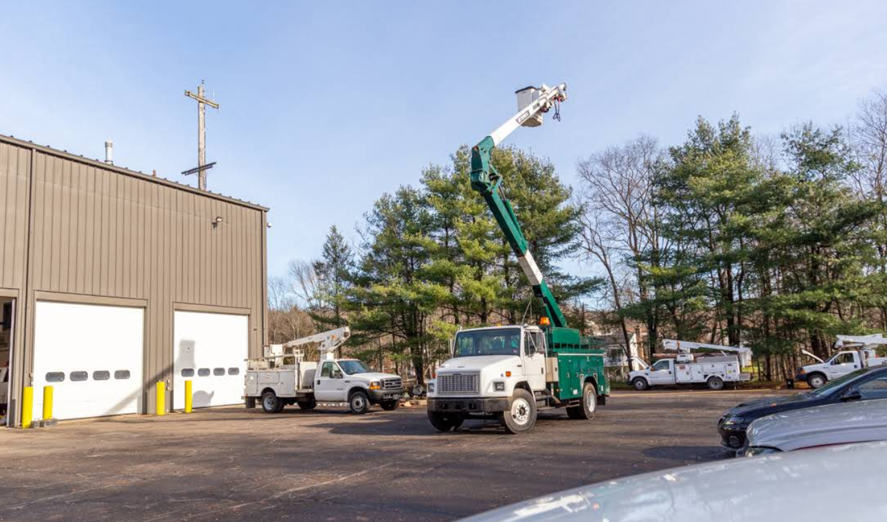 A truck with a crane on top of it is parked in front of a building.