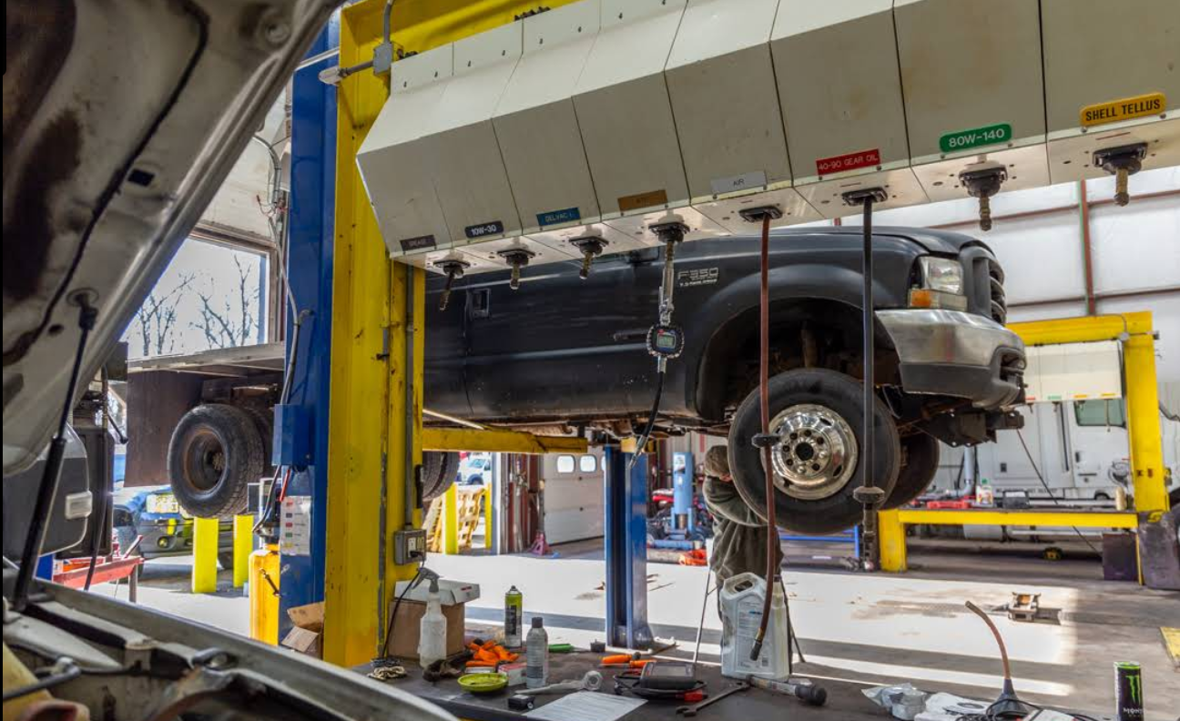 A truck is sitting on a lift in a garage.