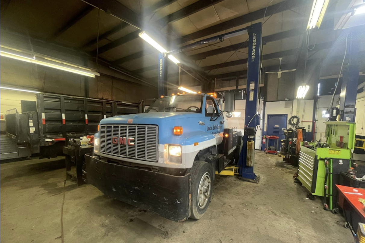 A blue truck is sitting on a lift in a garage.