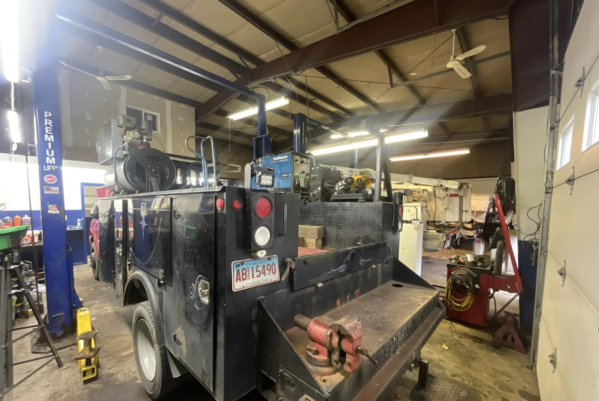 A black truck is parked in a garage next to a lift.