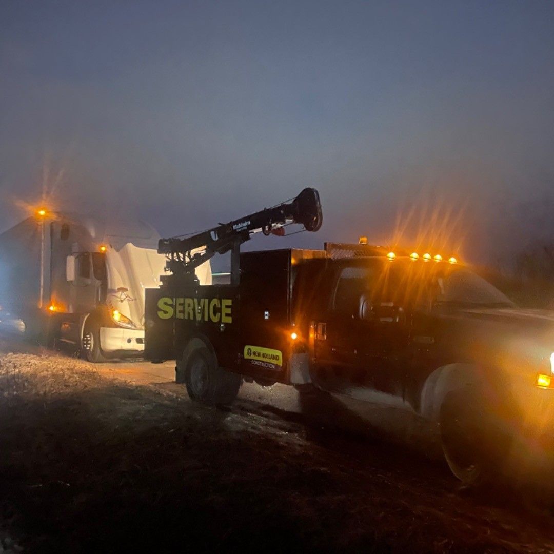 A tow truck with the word service on the back is parked next to a truck.