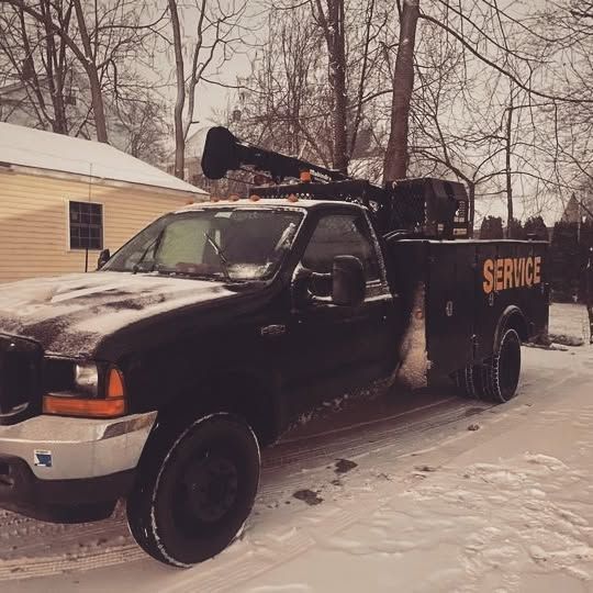 A black service truck is parked in the snow