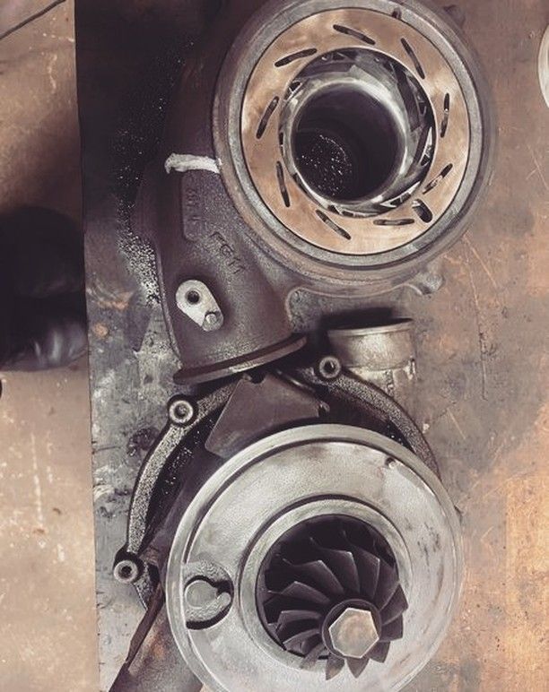 Two turbochargers are sitting on top of each other on a table.