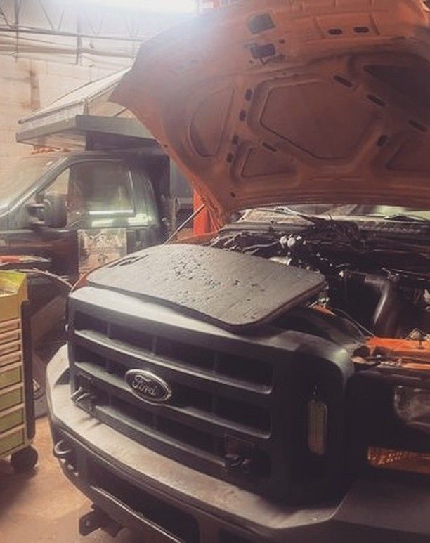 The hood of a ford truck is open in a garage.