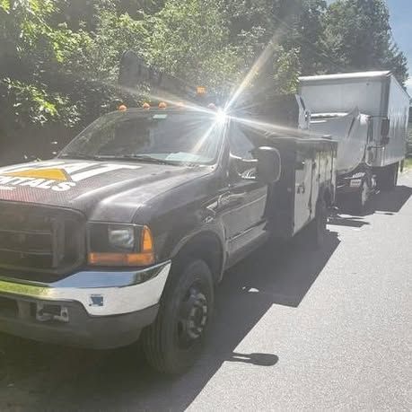 A black truck is parked on the side of the road next to a white trailer.