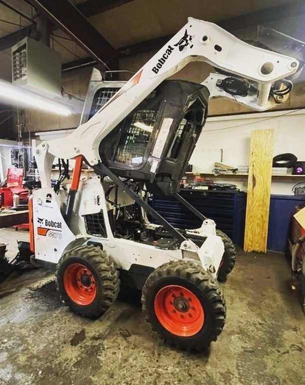 A bobcat is sitting in a garage with its hood up