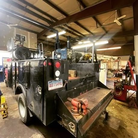 A black utility truck with a license plate that says ab15480 is parked in a garage.