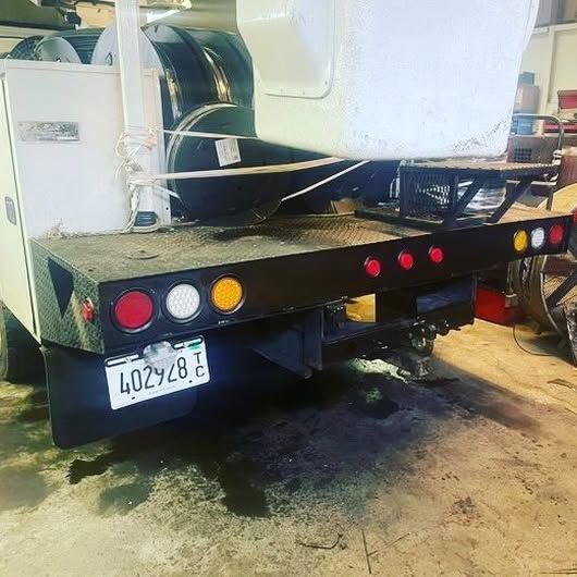 A white truck with a license plate that says 402928 is parked in a garage.