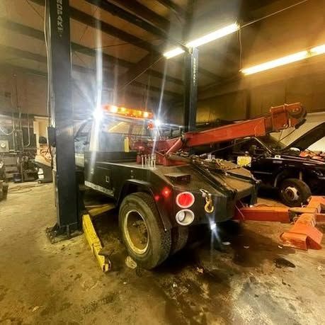 A tow truck is parked on a lift in a garage.