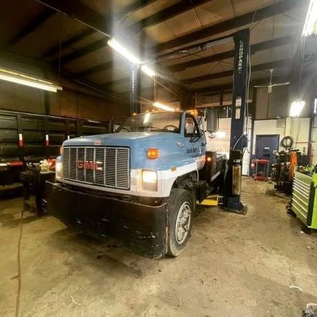 A blue truck is parked on a lift in a garage.