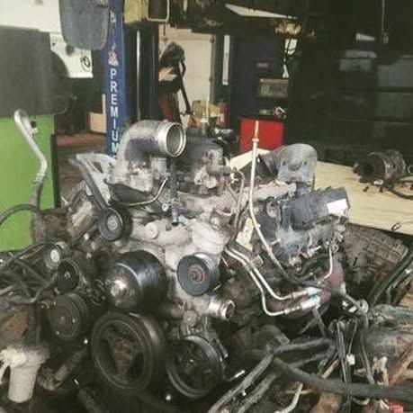 A large engine is sitting on top of a wooden table in a garage.