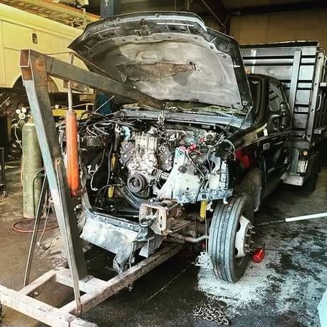 A truck with the hood up is being worked on in a garage.