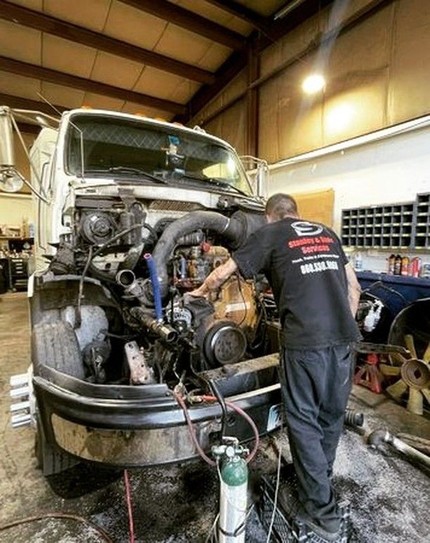 A man is working on the engine of a truck in a garage.