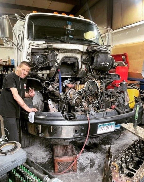 A man is working on the engine of a truck in a garage.