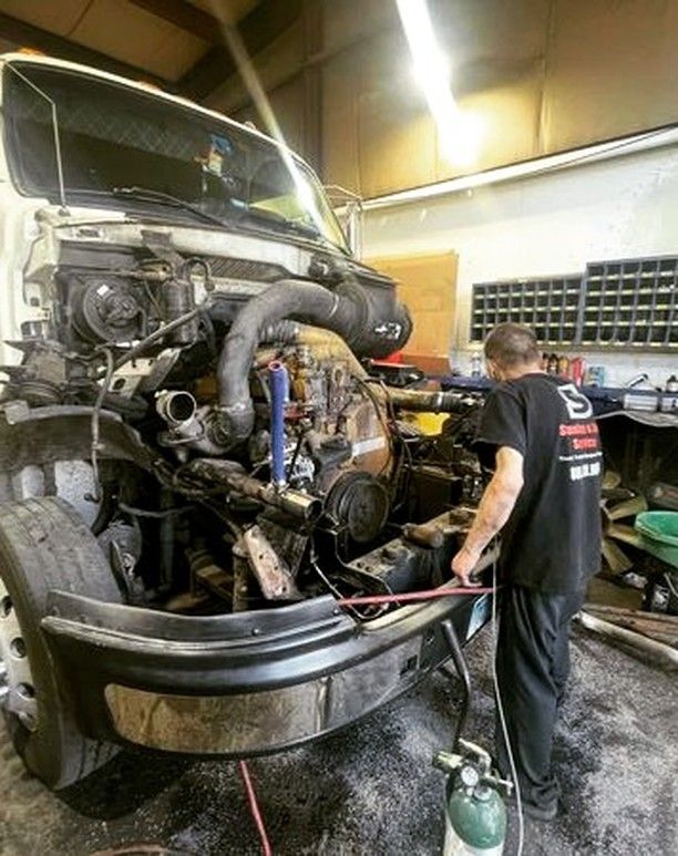 A man is working on a truck engine in a garage.