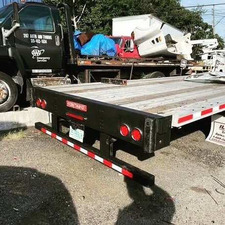 A tow truck with a flatbed is parked in a parking lot