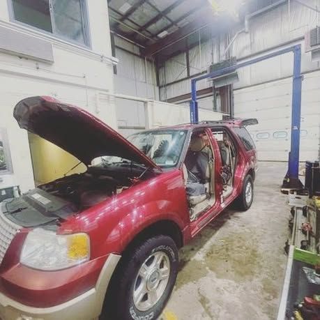 A red suv is parked in a garage with its hood open.