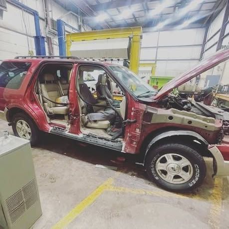 A red suv is sitting in a garage with its hood open.