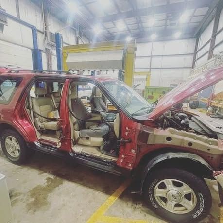 A red suv is sitting in a garage with its hood open.