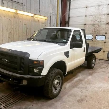 A white truck is parked in a garage next to a garage door.
