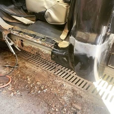 The side of a car is being repaired in a garage.