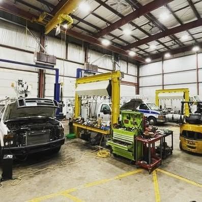 A car is being worked on in a garage with the hood open.