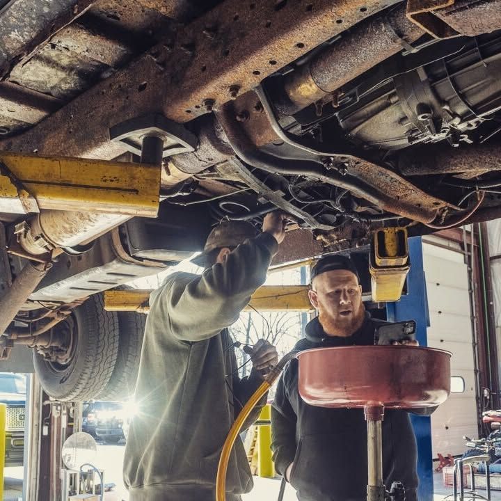 Two men are working under a truck in a garage