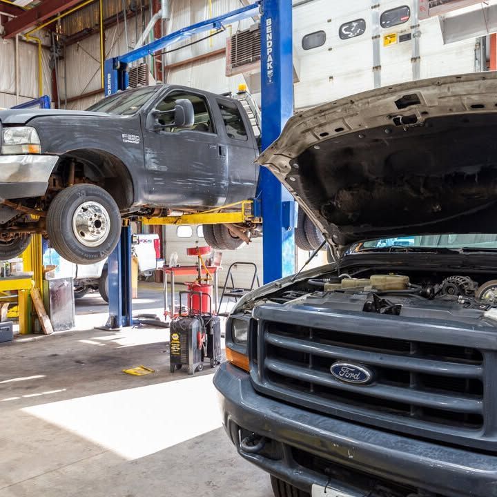 A ford truck is on a lift in a garage