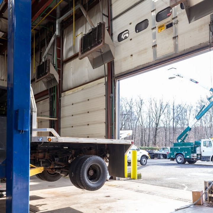 A truck is on a lift in a garage with the door open