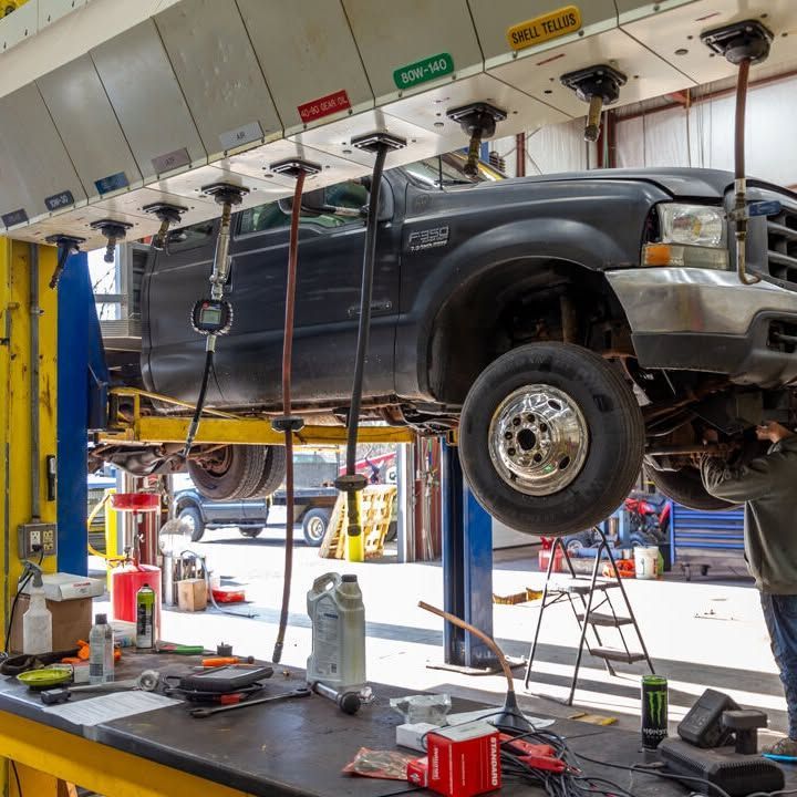 A black truck is being worked on in a garage