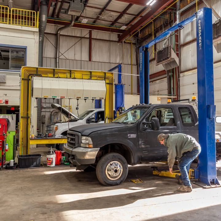 A man is working on a truck on a lift in a garage