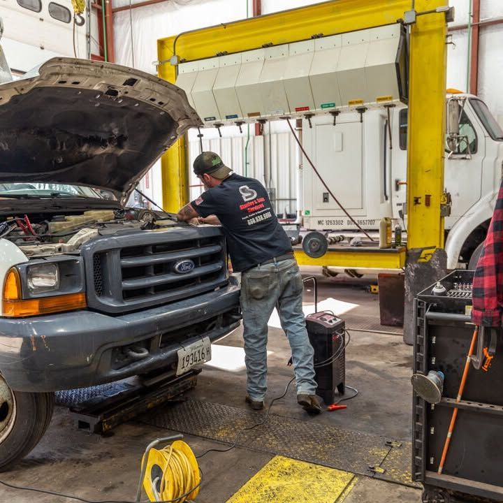 A man is working on a ford truck in a garage