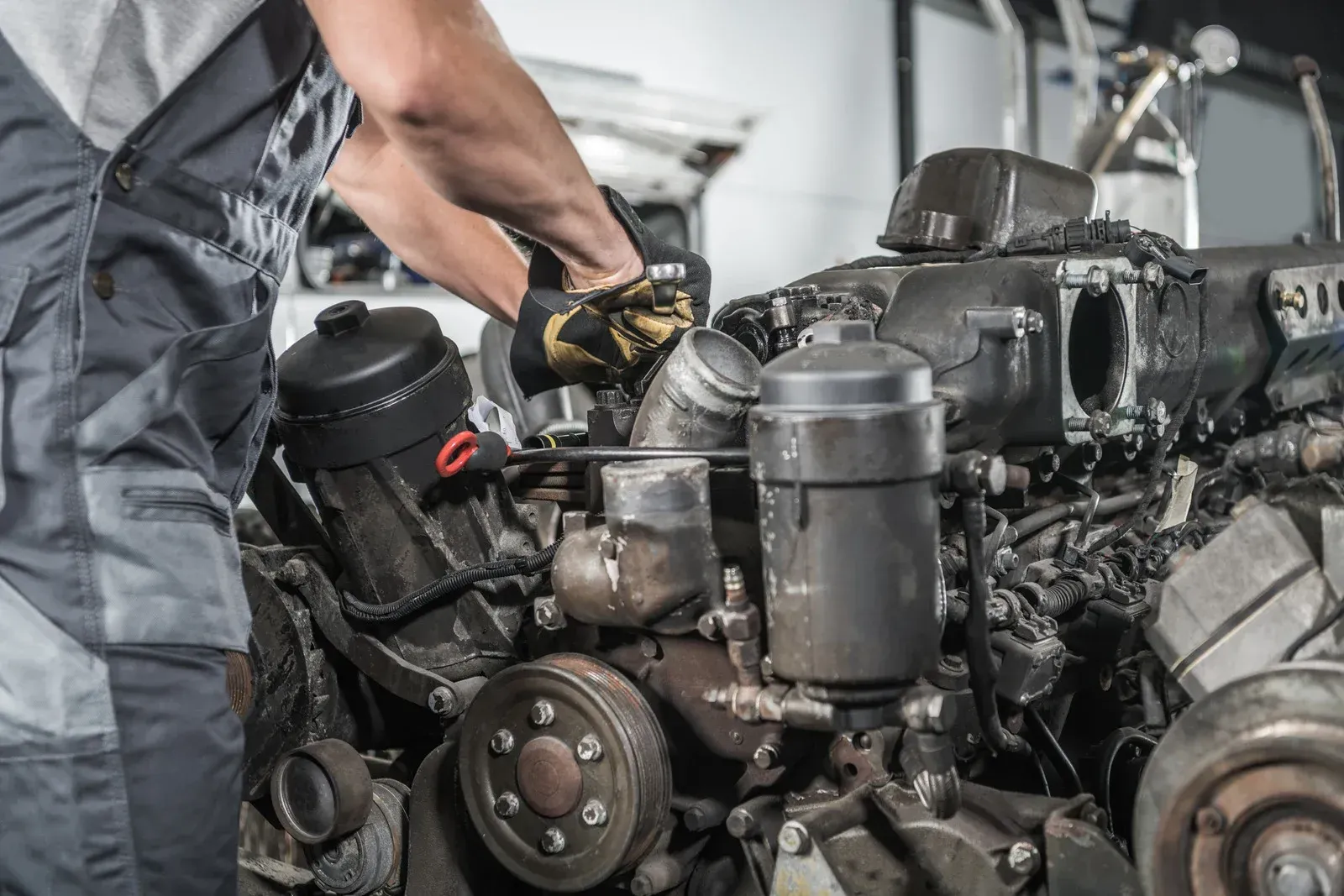 A man is working on a truck engine in a garage.