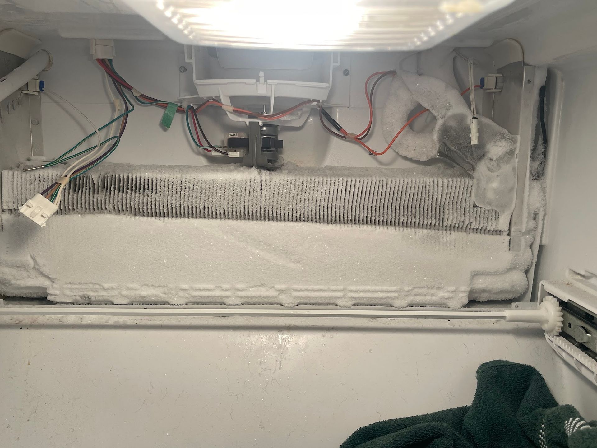 Frost-covered freezer interior. Exposed components, wires, and thick ice buildup.