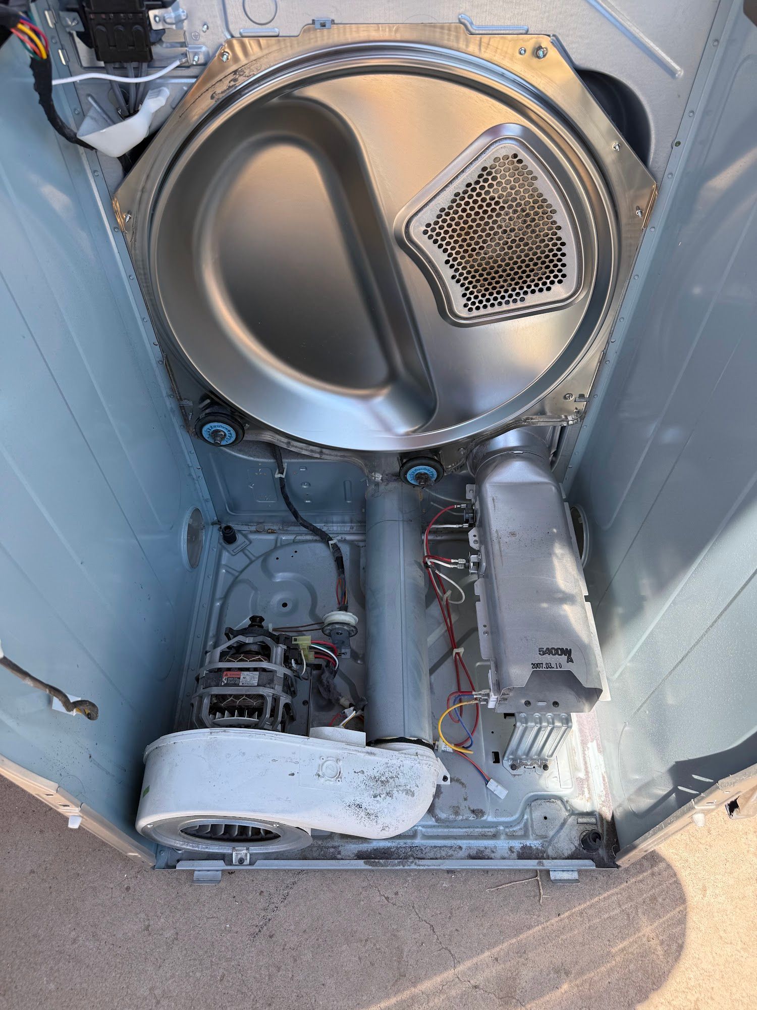 Interior of a dryer machine with the front panel removed, showing drum, heating element, and motor.